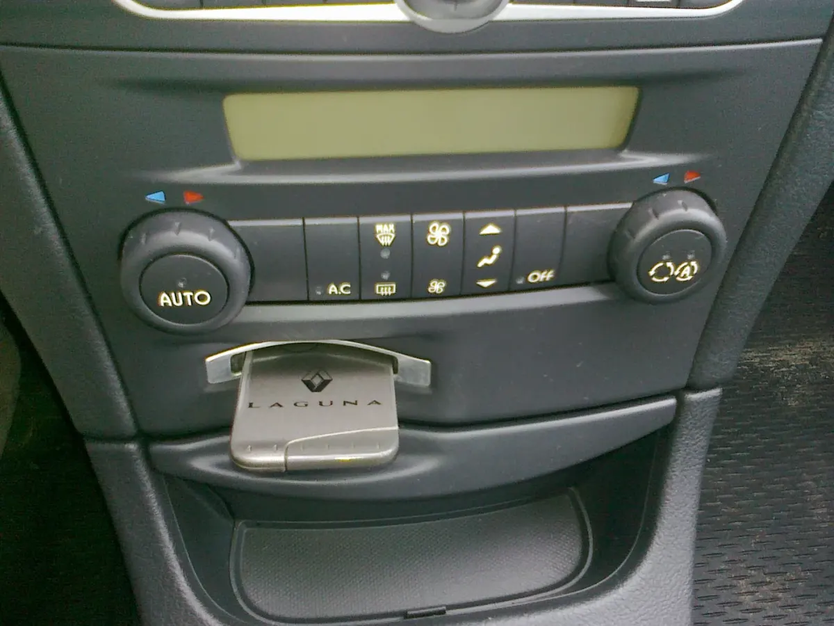 Panneau de commande de climatisation d’une Renault Laguna, avec deux molettes et une rangée de boutons de désembuage.