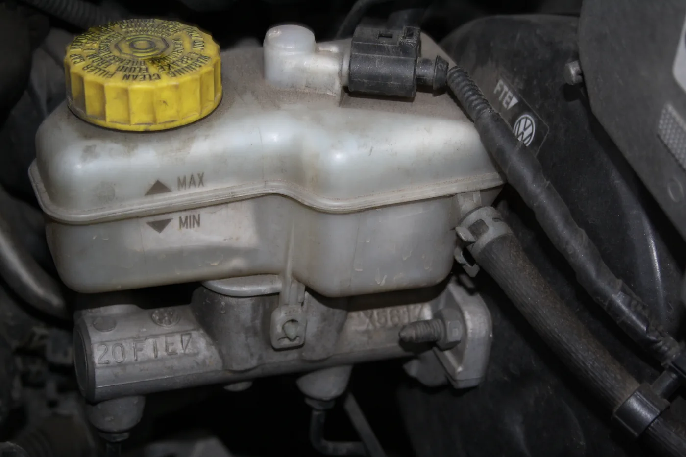 Réservoir de liquide de frein avec bouchon marqué « BRAKE FLUID » et repères MIN/MAX visibles.