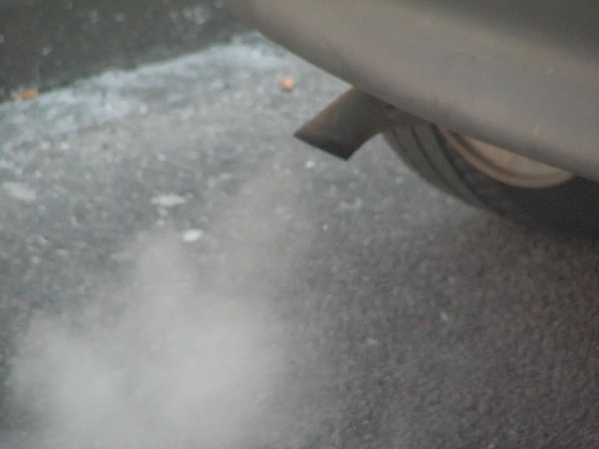 Gaz d’échappement qui sortent du pot d’une voiture, au ras du sol.