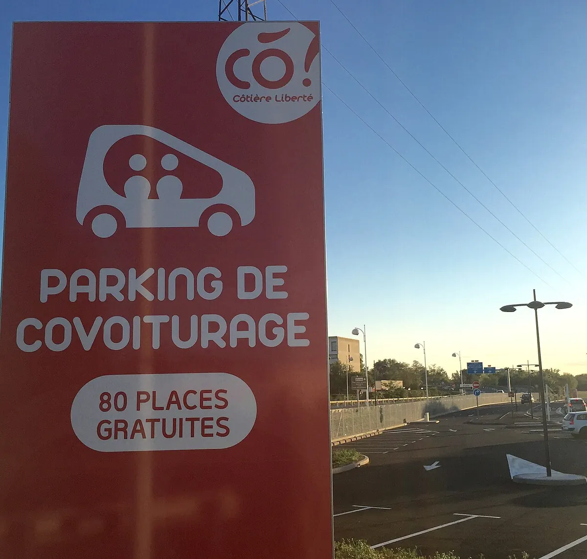 Panneau rouge « Parking de covoiturage, 80 places gratuites » à l’entrée d’une aire.