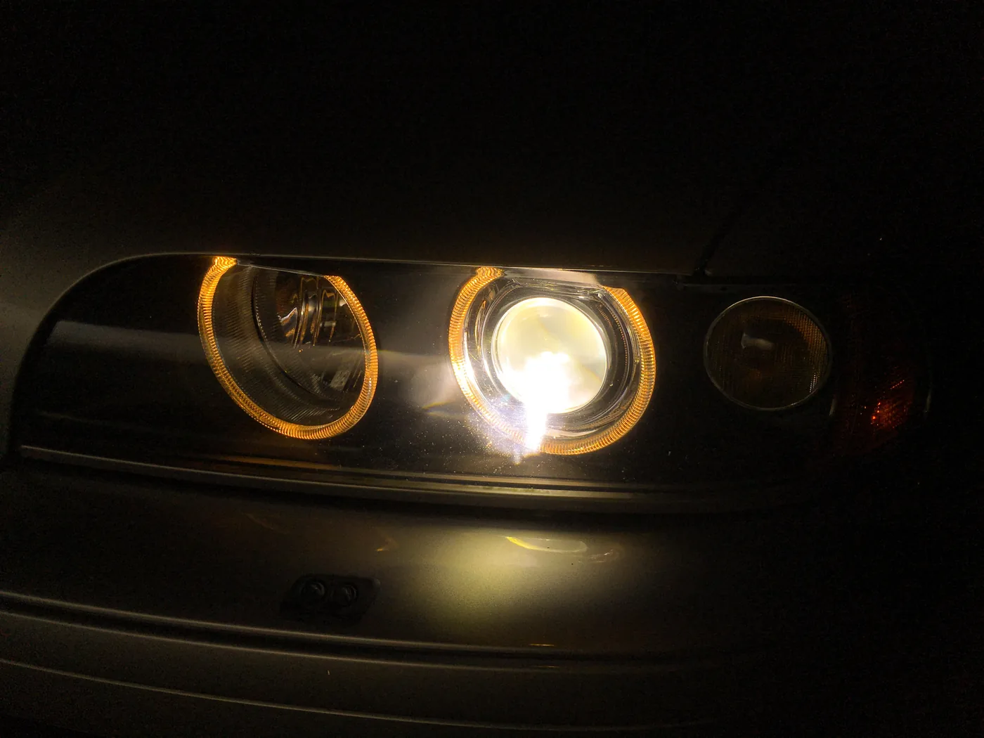 Gros plan d’un bloc optique avant de BMW E39, avec plusieurs éléments lumineux allumés.