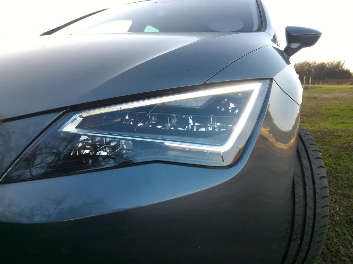 Bloc optique avant et signature lumineuse d’une Seat Leon III, bande de feux diurnes allumée.