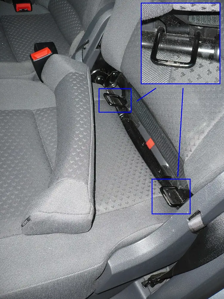 Banquette arrière dont l’assise est écartée pour montrer les deux anneaux d’ancrage Isofix, encadrés en bleu.