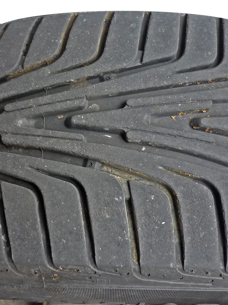 Marquage « TWI » sur l’épaule d’un pneu, à côté du petit relief traversant une rainure de la bande de roulement.